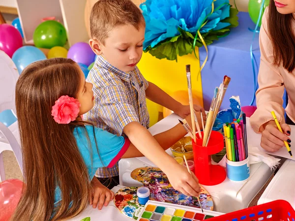 Niños con maestra pintando sobre papel en el jardín de infantes  . — Foto de Stock