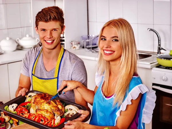 Glückliches Paar kocht Huhn in der Küche. — Stockfoto