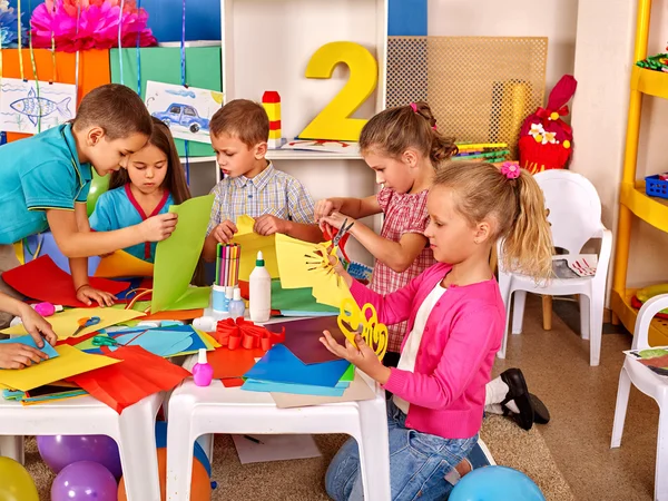 Dzieci trzymanie kolorowego papieru na stole w przedszkolu . — Zdjęcie stockowe