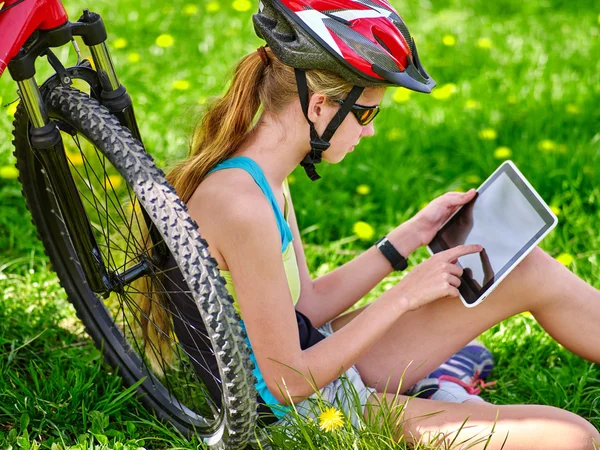 Bicicletas menina ciclismo usando capacete no ciclismo sentado perto de bicicleta e assistir pc tablet . — Fotografia de Stock