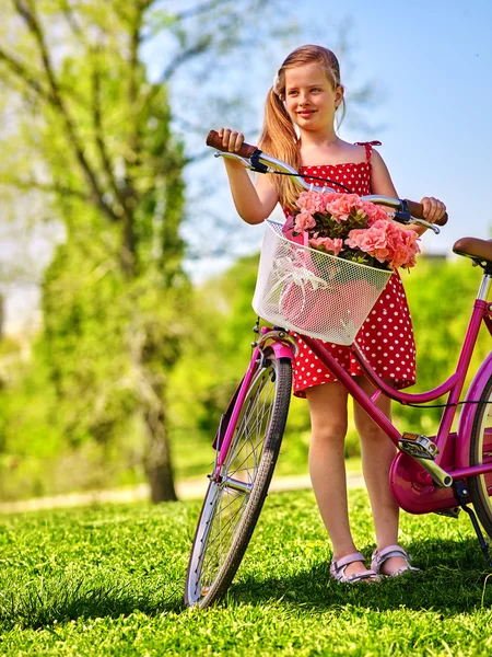 Child girl wearing white polka dots dress rides bicycle . — Stock Photo, Image