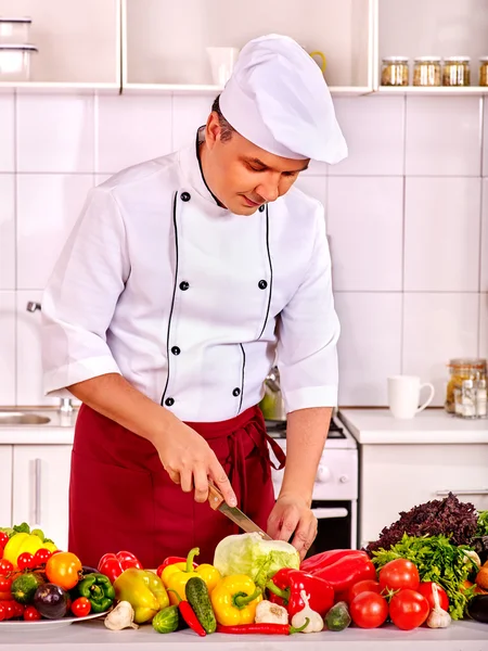 Homme heureux dans le chapeau de chef cuisine salade de légumes frais . — Photo