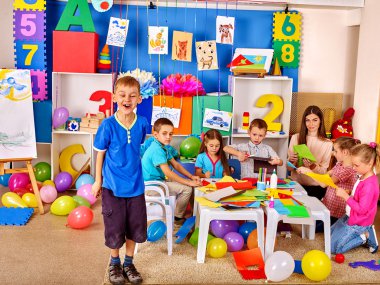 Anaokulunda masa üzerinde renkli kağıt ile çalışan çocuklar .