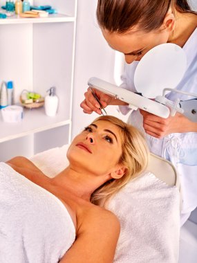 Spa salonda orta yaşlı kadın. Güzellik uzmanı tarafından tweezing kaş.
