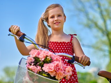 Çocuk kız giyiyor kırmızı puantiyeli elbise bisiklet ile gidiyor.