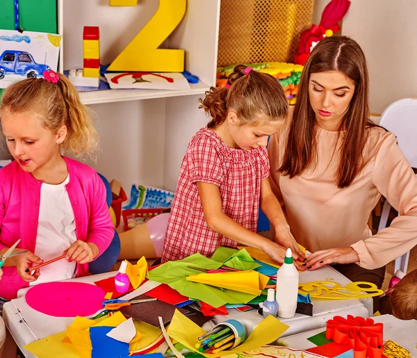 Barn som håller färgat papper på bordet i dagis . — Stockfoto