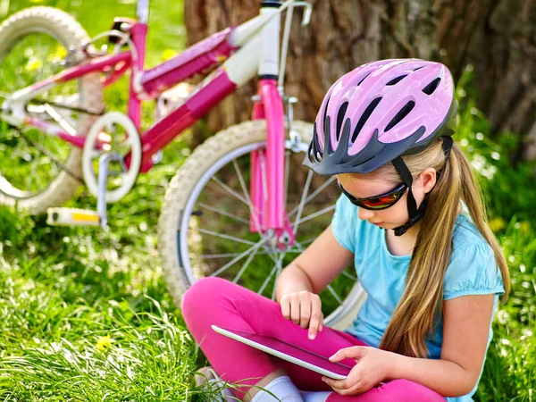 자전거 자전거 소녀 착용 헬멧 시청 에 태블릿 PC . — 스톡 사진