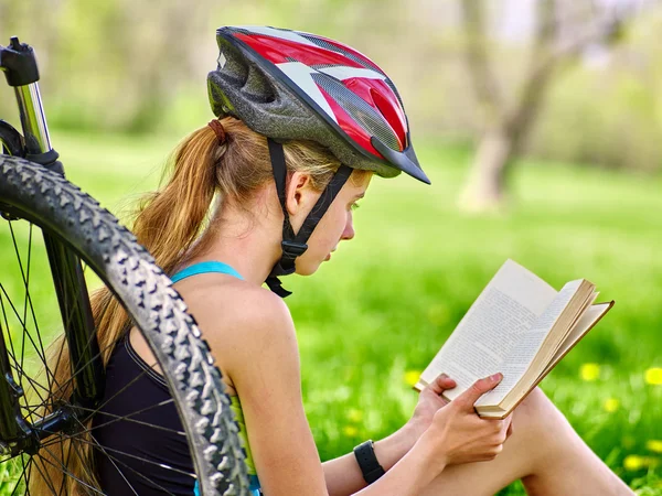 Bicicletas ciclismo menina vestindo capacete ler livro resto perto de bicicleta . . — Fotografia de Stock
