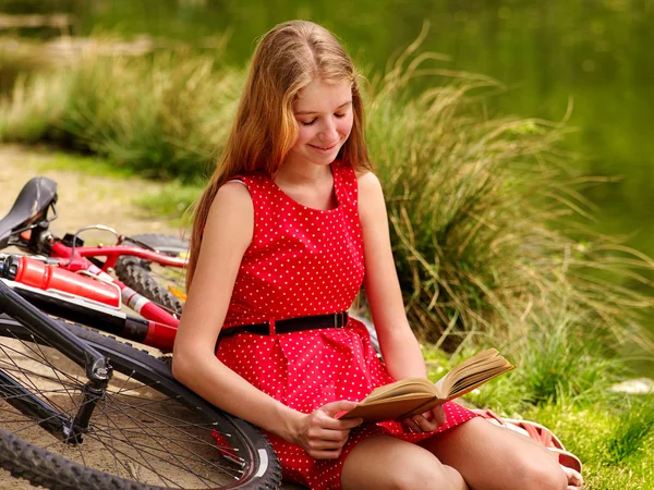 Vélos vélo fille dans le parc lire livre vélo sur le rivage . — Photo