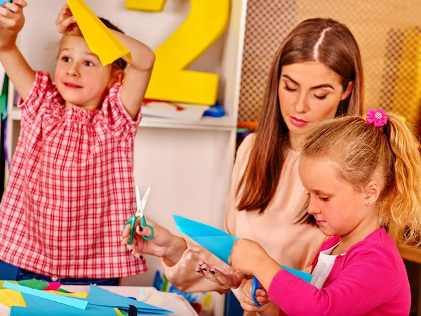 Kinderen houden gekleurd papier op tafel in de kleuterschool . — Stockfoto