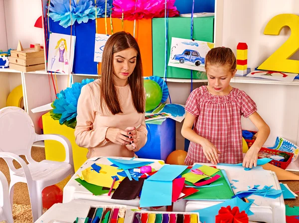 Kinder halten buntes Papier auf Tisch im Kindergarten . — Stockfoto