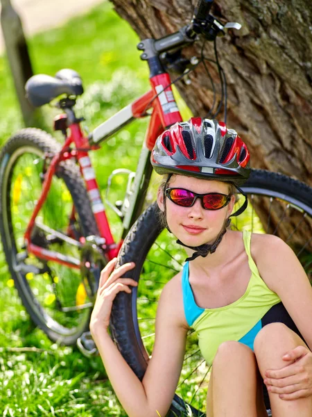 Ποδήλατα, ποδηλασία κοπέλα φορώντας κράνος έχουν υπόλοιπο κάθεται κάτω από δέντρο. — Φωτογραφία Αρχείου