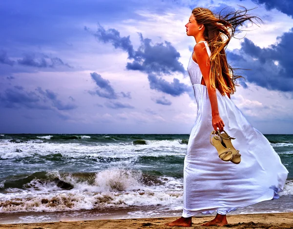 Meisje loopt strand zee tegen hemel en wolken. — Stockfoto