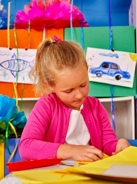 Kid holding colored paper on table in kindergarten . — ストック写真