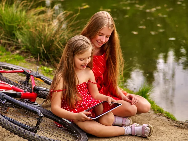Barn med Tablet PC nära cykel till floden i parken . — Stockfoto