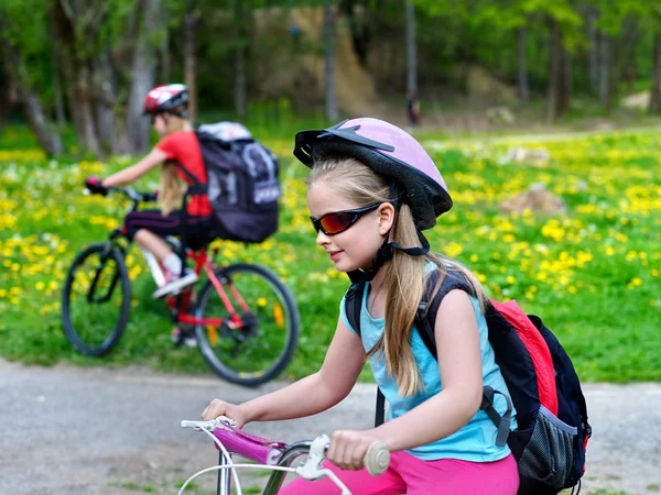 Kinder fahren Fahrrad auf grünem Gras und Blumen im Park. — Stockfoto