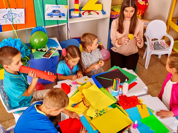 Los niños con maestro están haciendo algo con papel de colores. . — Foto de Stock