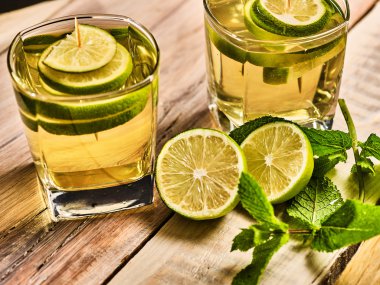 Ahşap kurullarında yeşil şeffaf içkiyle bardaklar.