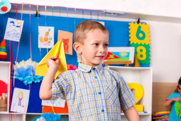 Criança brincando com origami avião na escola primária . — Fotografia de Stock