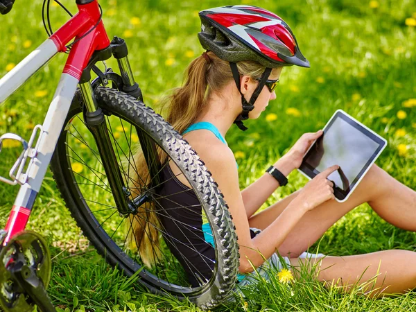 Menina vestindo capacete ciclismo sentado perto de bicicleta assistir pc tablet . — Fotografia de Stock