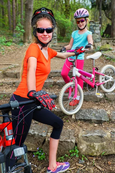 Bikes family. Mother and daughter wearing helmet cycling on bicycles .