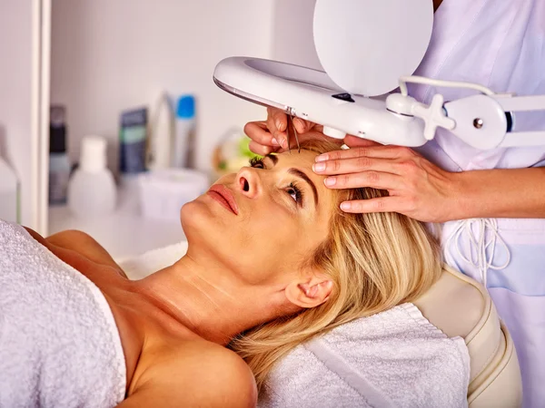 Woman middle-aged in spa salon. Tweezing eyebrow by beautician. — Stock Photo, Image