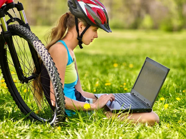 Cykling flicka bär hjälm cykling sitter nära cykel klocka laptop. — Stockfoto