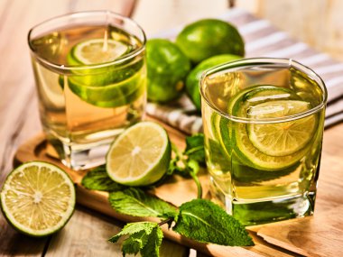 Ahşap kurullarında yeşil şeffaf içkiyle bardaklar.