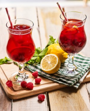 Ahşap kurullarında iki bardak kırmızı ahududu kokteyl ile buz