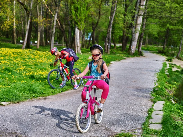 Barn rida cykel på grönt gräs och blommor i park. — Stockfoto