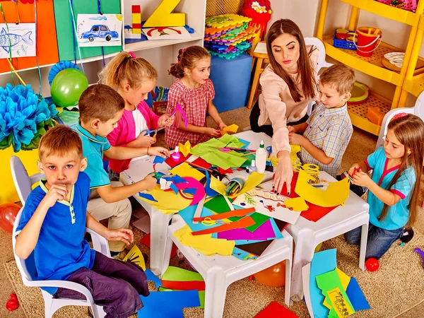 Kinder mit Lehrerin basteln etwas aus buntem Papier. — Stockfoto