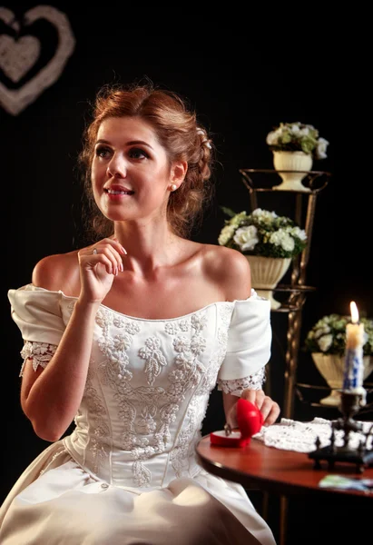 Gelukkig meisje in een trouwjurk zit aan tafel. — Stockfoto