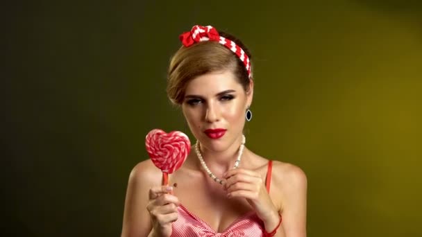 Girl in pin-up style lick striped lollipops. — Stock Video