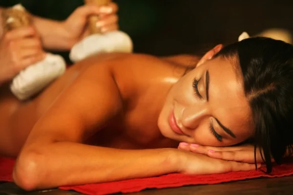 Mujer joven tienen masaje de cataplasma caliente en el salón de spa . — Foto de Stock