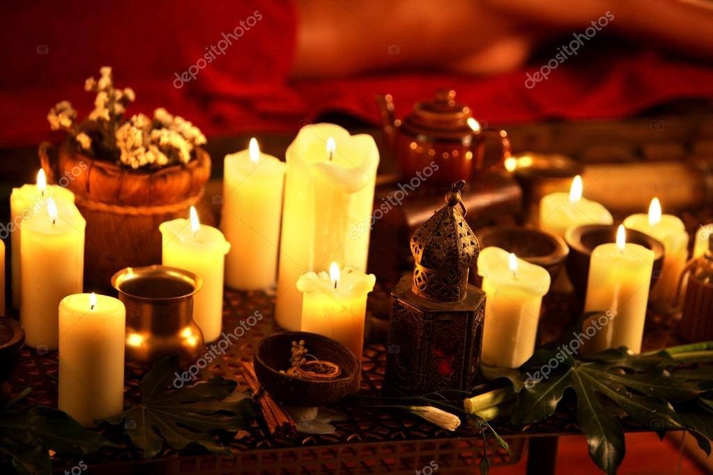 Still life with burning candles and massage herbs. Stock Photo by