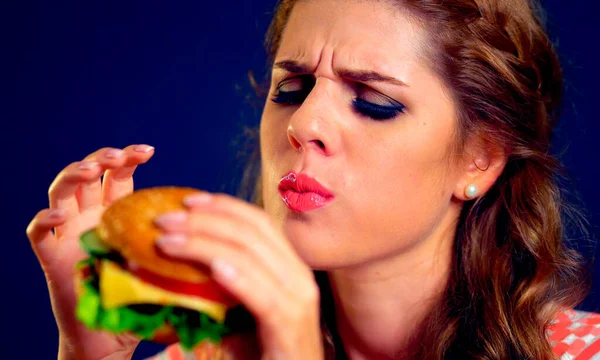 Hamburger yiyen bir kadın. Mutlu bir kızın iştah açıcı yüzü abur cubur yer. . — Stok fotoğraf