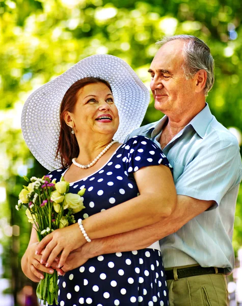 Feliz pareja de ancianos con flores . — Foto de Stock