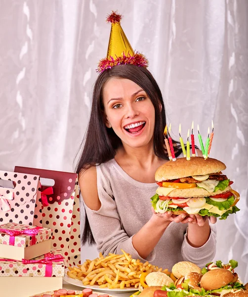 Woman eating hamburger at birthday. Stock Photo