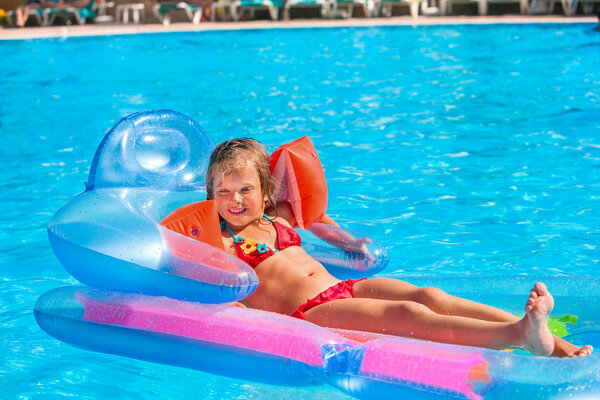 Child swimming on inflatable beach mattress.