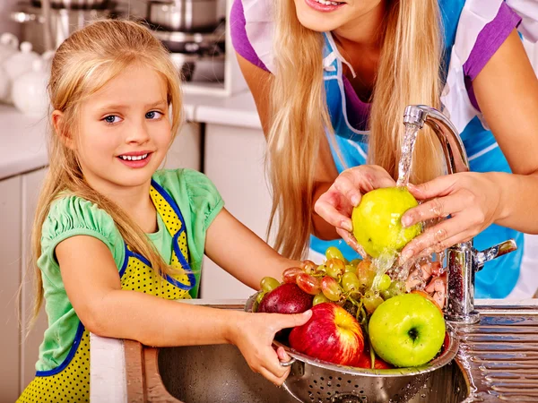 Mor och dotter tvätta frukter på kök. — Stockfoto