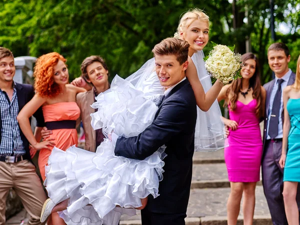 Groom carries his bride over shoulder. — Stock Photo, Image