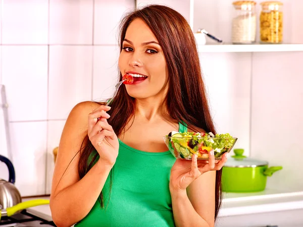 Mulher comendo salada na cozinha . — Fotografia de Stock