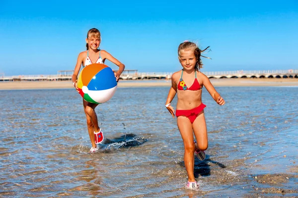 Crianças segurando bola correndo na praia . — Fotografia de Stock
