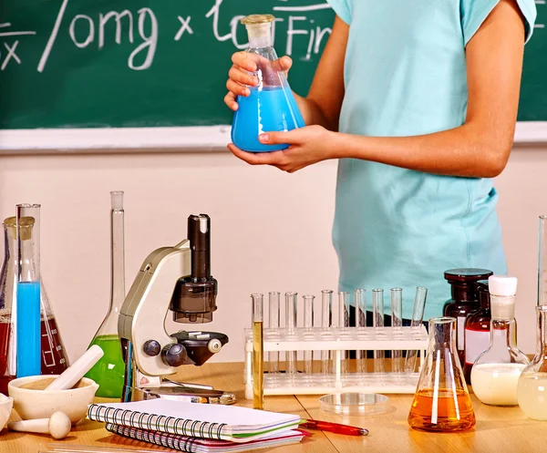 Kid hospodářství baňka v hodinách chemie. — Stock fotografie