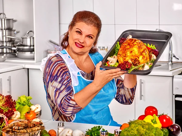 Mulher madura preparando frango na cozinha . — Fotografia de Stock