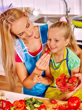 Mother feed child at kitchen. clipart