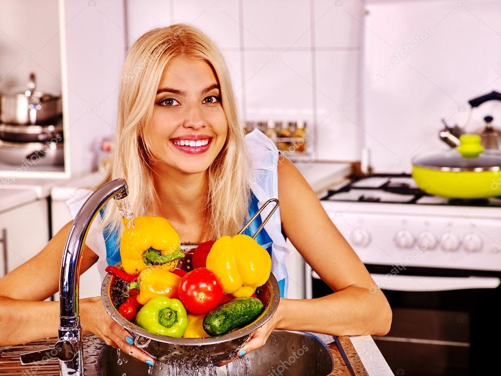 Woman washes vegetables  at kitchen.