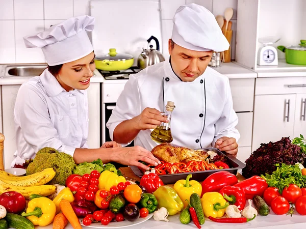 Homem e mulher em chapéu de chef cozinhar frango — Fotografia de Stock