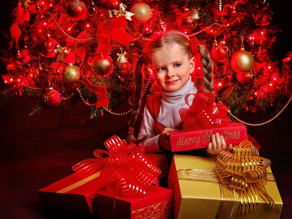 Child holding gift box near Christmas tree. — Stock Photo, Image