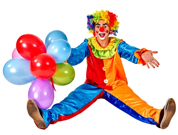 Gelukkige verjaardag clown houden van een bos van ballonnen en zittend op de vloer. Rechtenvrije Stockafbeeldingen